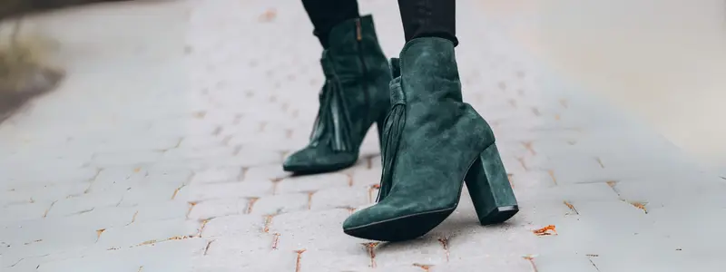 Autumn ankle suede boots in bottle green, with a model walking on the sidewalk