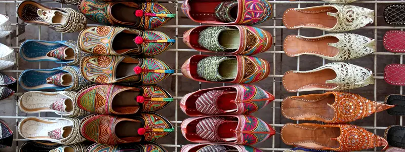 A bazaar display filled with exotic, colorful shoes in traditional styles.