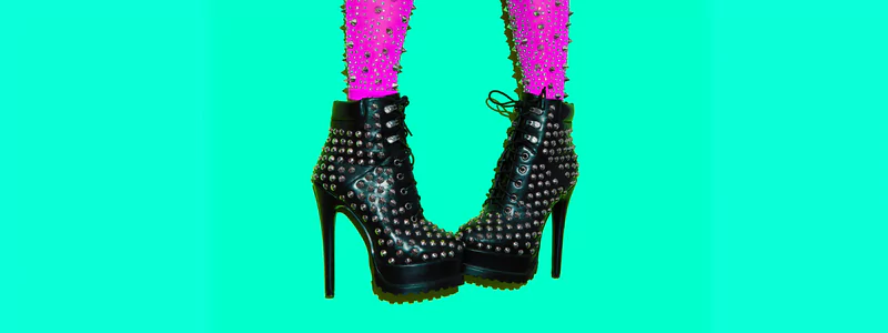 A rock-inspired person wearing studded pink tights and black ankle boots with stiletto heels and a platform.