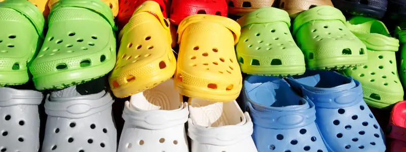 Colorful Crocs-style clogs with signature holes and an ankle strap.