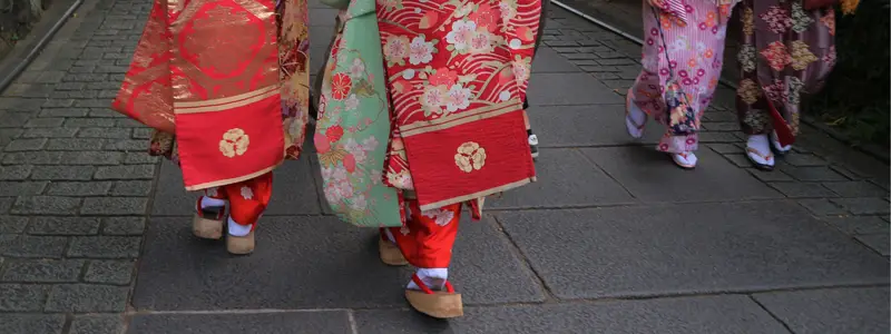 Japanese women walking in colorful kimonos and traditional high wooden sandals.