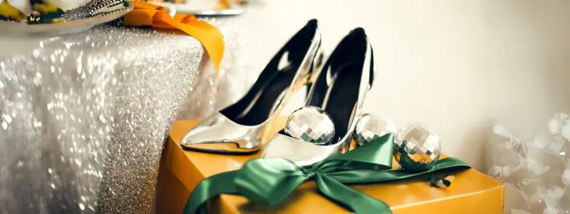 Silver elegant stiletto shoes lying on a New Year's gift.