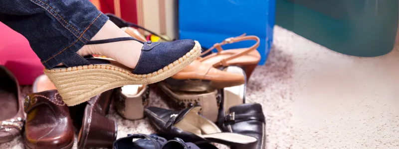 Wedge Heels: Versatile & Convenient Classic 3 A person trying on Wedge Heels sandals, with many other high-heeled and flat shoes scattered on the floor.