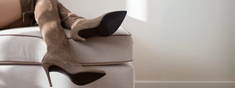 Suede heels: Indulgent Softness 4 A person relaxing on a pouf in over-the-knee brown boots made of vegan suede.