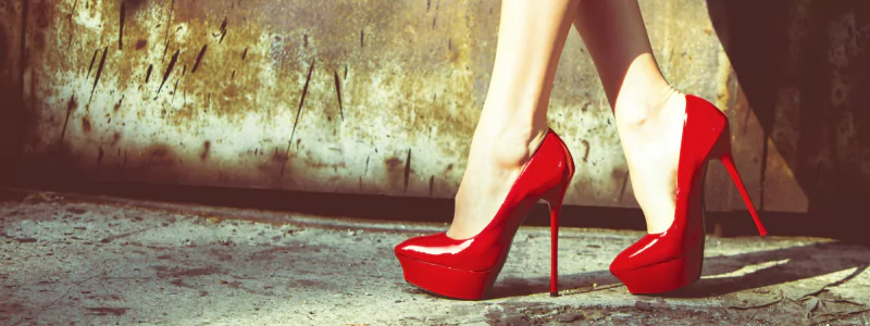 GTA 6 Heels: Genius Game-Changer? 2 Killer bright red platform heels in a gritty industrial setting with a stained concrete floor and a shabby wall.