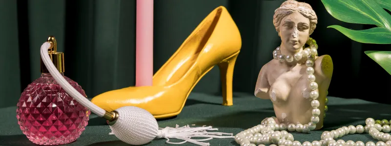 Late 20th-century women's accessories, including colorful high heels, pink perfume, and beads.