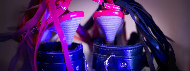 Erotic pink high heels with a striped conical heel inserted into massive leather cuffs.