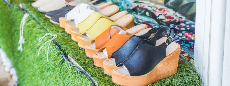 Storage Hacks for Your Men’s Heels: Organize Boldly, Hide Beautifully 3 Colorful wedge sandals for all genders displayed in a row on artificial grass – inclusive summer shoe options for men who wear heels.
