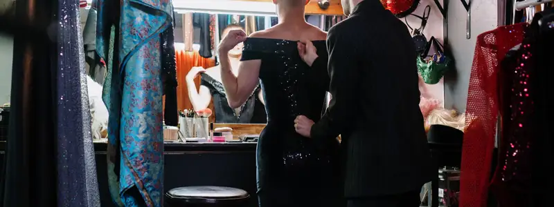 Person trying on an elegant evening dress in a luxury fitting room, preparing a sophisticated high-fashion look often styled with designer high heels.